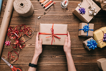 Image showing Crop hands holding wrapped present on table