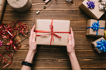 Image showing Crop hands holding wrapped present on table