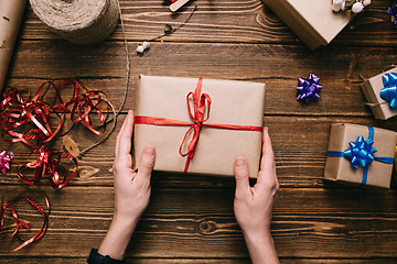 Image showing Crop hands holding wrapped present on table