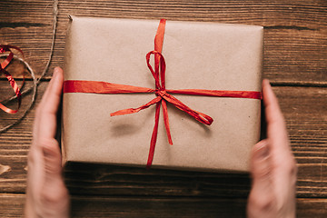 Image showing Crop hands holding wrapped present on table