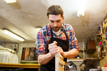 Image showing carpenter working with plane and wood at workshop