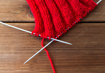 Image showing hand-knitted item with knitting needles on wood