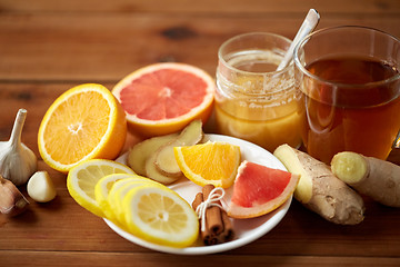 Image showing ginger tea with honey, citrus and garlic on wood