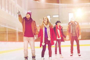 Image showing happy friends pointing finger on skating rink