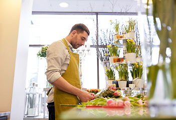 Image showing smiling florist man making bunch at flower shop