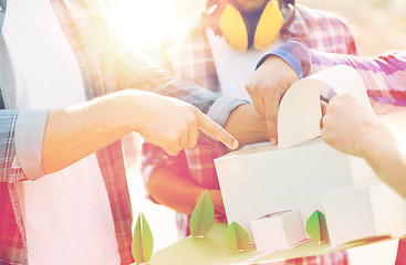 Image showing close up of builders with paper house model