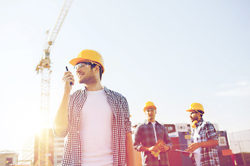 Image showing group of smiling builders in hardhats with radio