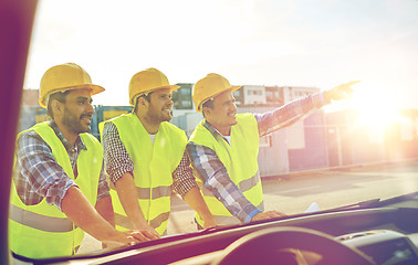 Image showing close up of builders with blueprint on car hood