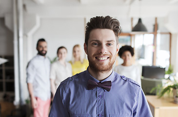 Image showing happy young man over creative team in office