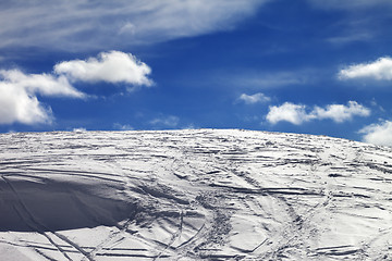 Image showing Off-piste slope with track from ski and snowboard and blue sky w