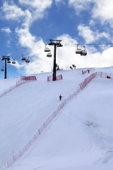 Image showing Skier ascend on snow ski slope and ski-lift at evening