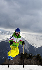 Image showing Young skier jump with ski poles in sun winter mountains