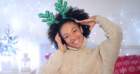 Image showing Playful young woman wearing green reindeer antlers
