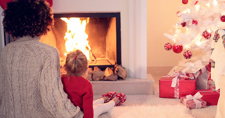 Image showing Mother and child warm up by the fireplace