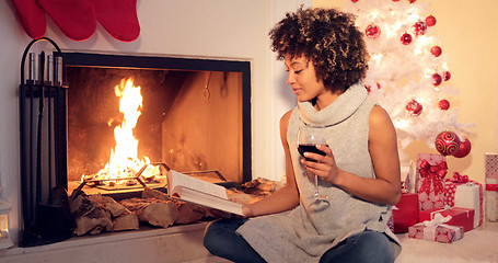 Image showing Young woman reading a drinking red wine