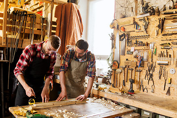 Image showing carpenters with ruler and wood plank at workshop