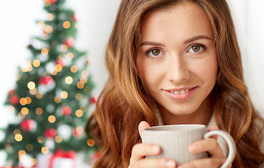 Image showing close up of woman with tea cup over christmas tree