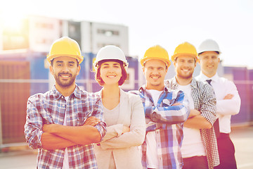 Image showing group of smiling builders in hardhats outdoors