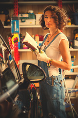 Image showing woman mechanic in blue overalls with instructions for repair and