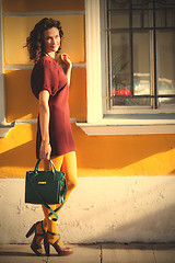 Image showing beautiful smiling woman in a burgundy dress with green handbag