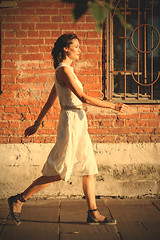 Image showing beautiful woman in a white dress goes on old street