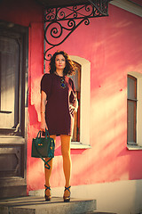 Image showing pretty woman in a burgundy dress with a green handbag