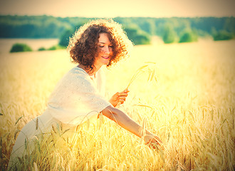 Image showing smiling woman in a light dress collects in the ears of the field