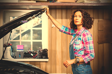 Image showing beautiful woman mechanic in blue overalls and a plaid shirt near