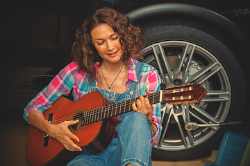 Image showing woman car mechanic with guitar in garage