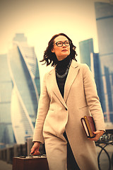 Image showing beautiful brunette in light coats with books and wooden briefcas