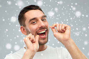 Image showing man with dental floss cleaning teeth over snow