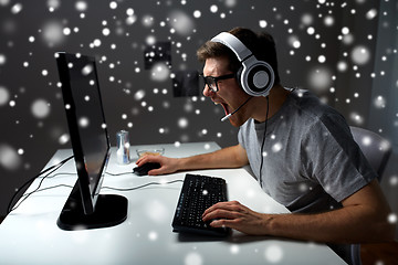 Image showing man in headset playing computer video game at home