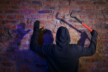 Image showing Burglar surrenders against brick wall