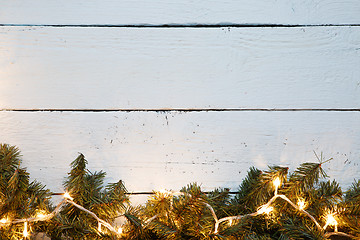 Image showing Wooden surface decorated with fir branches and lightbulb. Christmas card