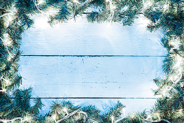 Image showing Christmas light blue wooden background with lightbulb and spruce branches