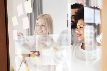 Image showing happy creative team writing on stickers at office