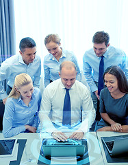 Image showing smiling business people with laptop in office