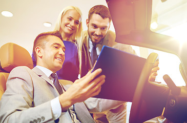 Image showing happy couple with car dealer in auto show or salon