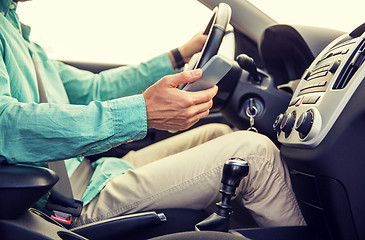 Image showing close up of man with smartphone driving car