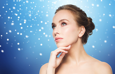 Image showing beautiful young woman touching her face over snow