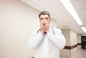 Image showing sad or crying male doctor at hospital corridor