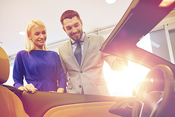 Image showing happy couple buying car in auto show or salon