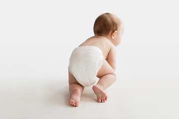 Image showing little baby in diaper crawling on white floor