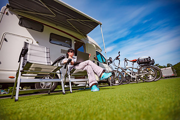 Image showing Woman sitting on a chair near the camper and looking at a laptop