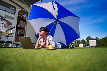 Image showing Woman on the grass, looking at the laptop under umbrella near th