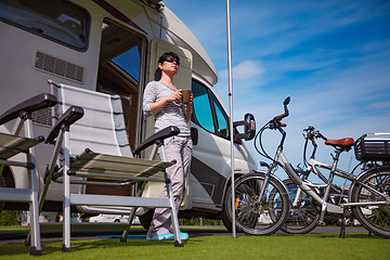 Image showing Woman is standing with a mug of coffee near the camper.