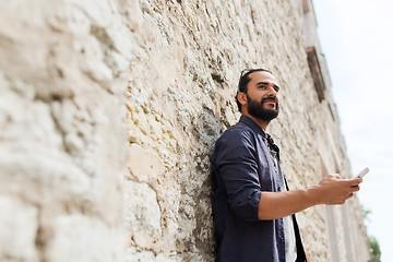 Image showing man with smartphone at stone wall