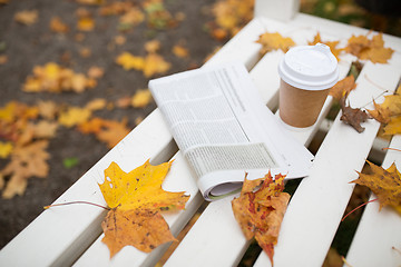 Image showing newspaper and coffee cup on bench in autumn park