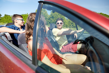 Image showing happy friends driving in cabriolet car and talking