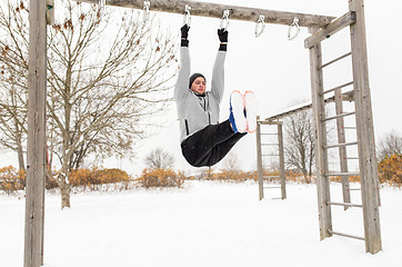 Image showing young man exercising on horizontal bar in winter